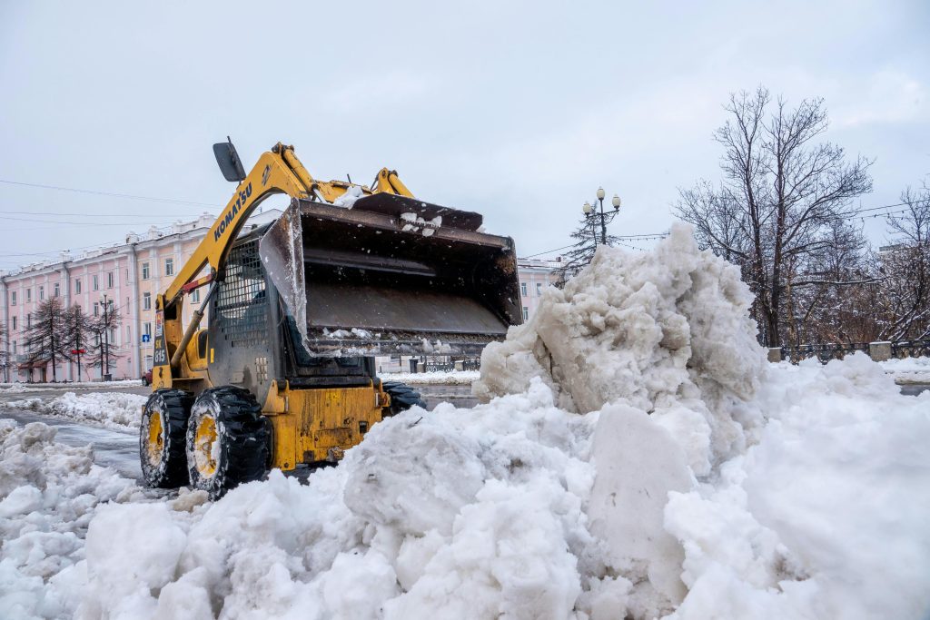 A bulldozer clearing snow in a city street during winter, showcasing heavy machinery in action.